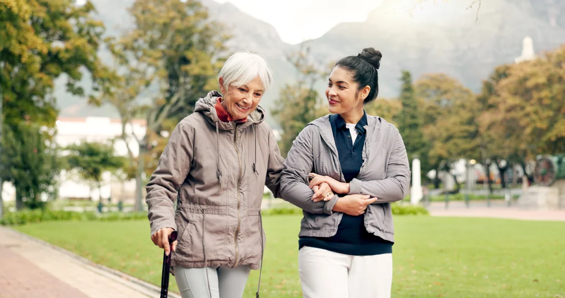 Senior woman walking with professional memory care caregiver in Tucson AZ